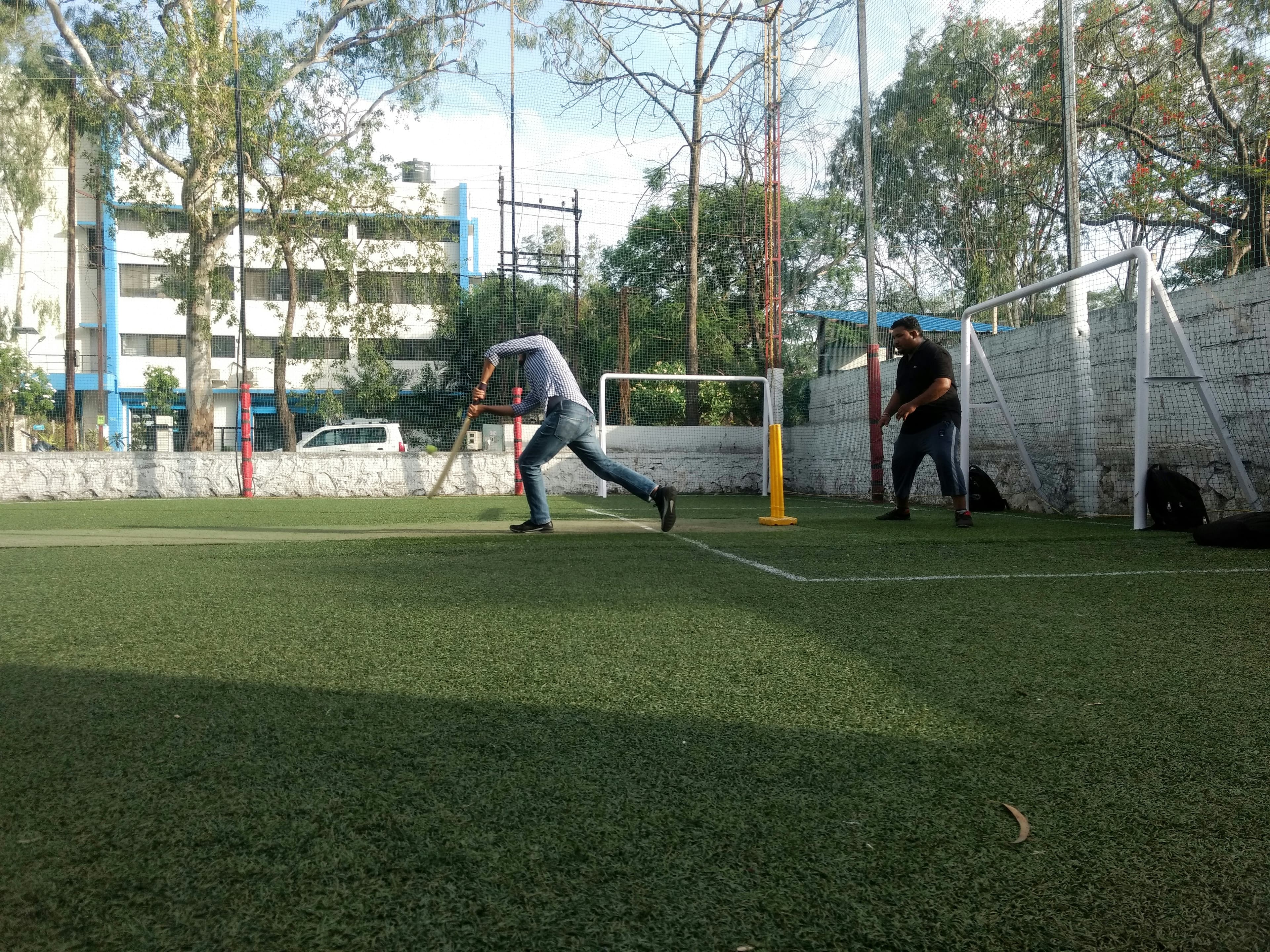 A batter drives on an artificial-turf box-cricket ground