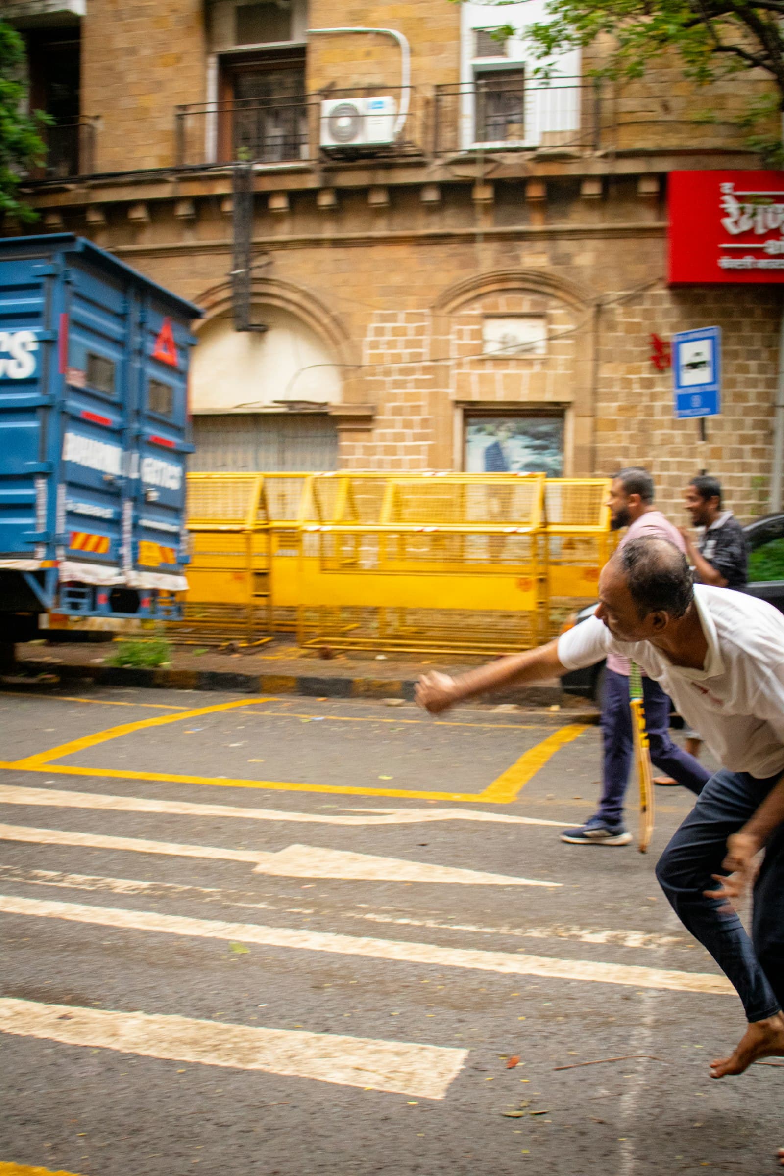 A bowler steams in on a city street lined with old buildings, a parked truck and a yellow barrier